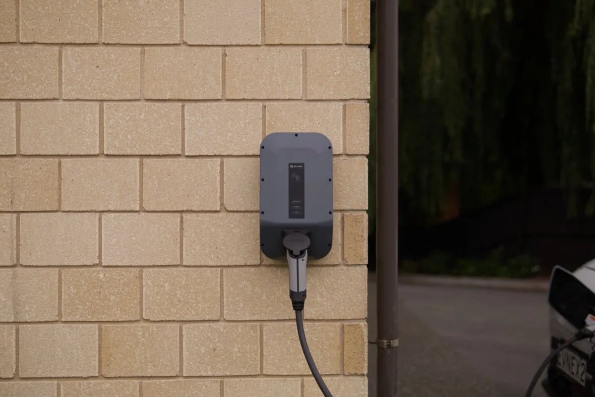 Borne de recharge murale pour voiture électrique, câble branché sur le boîtier au droit du stationnement