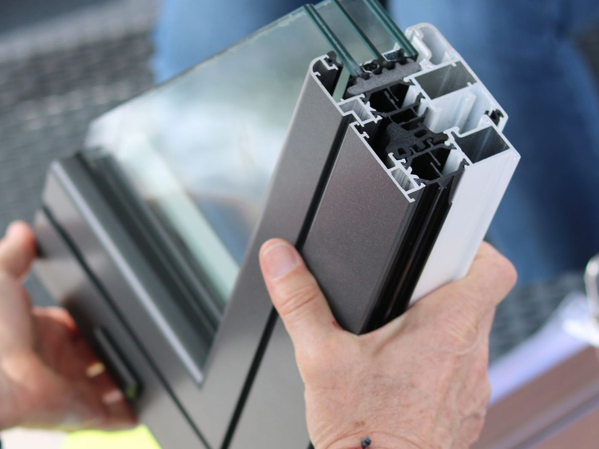 Profilé en aluminium thermolaqué gris anthracite tenu en main, face laquée et coupe du profilé visibles