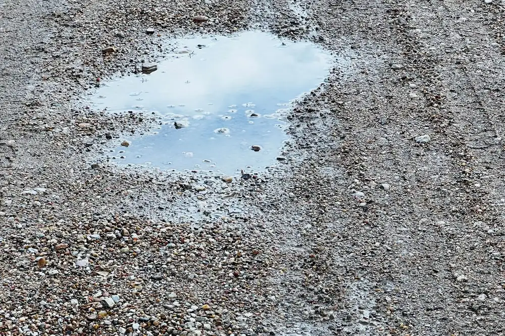 Flaque d'eau stagnante creusée dans un sol en gravier après la pluie