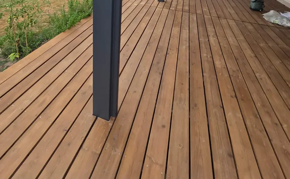 Pied d'un poteau de pergola aluminium posé au milieu d'une terrasse en bois, chantier en Gironde