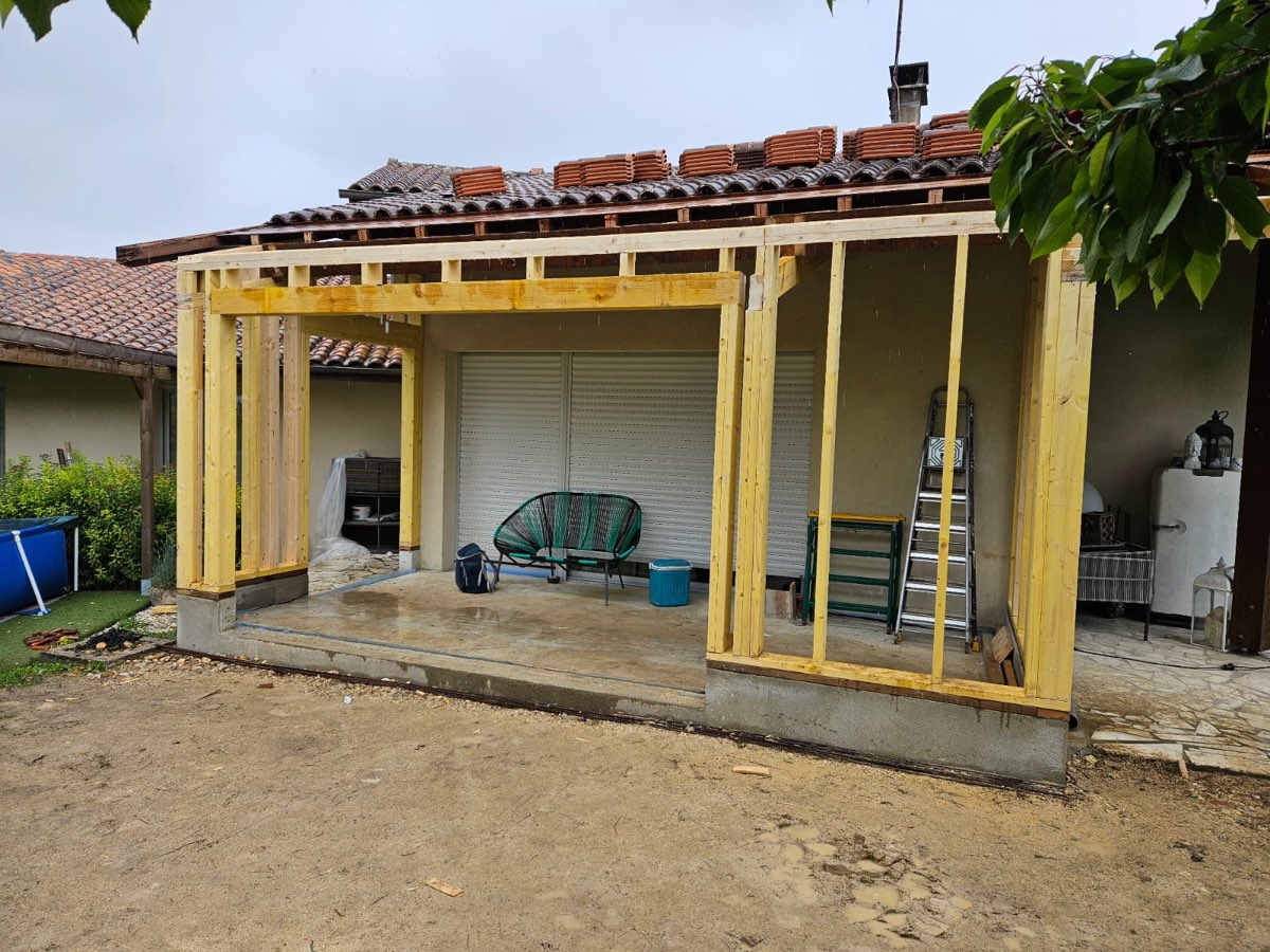 Montage de l'ossature bois d'une extension sur un chantier en Gironde, structure montée contre la maison existante