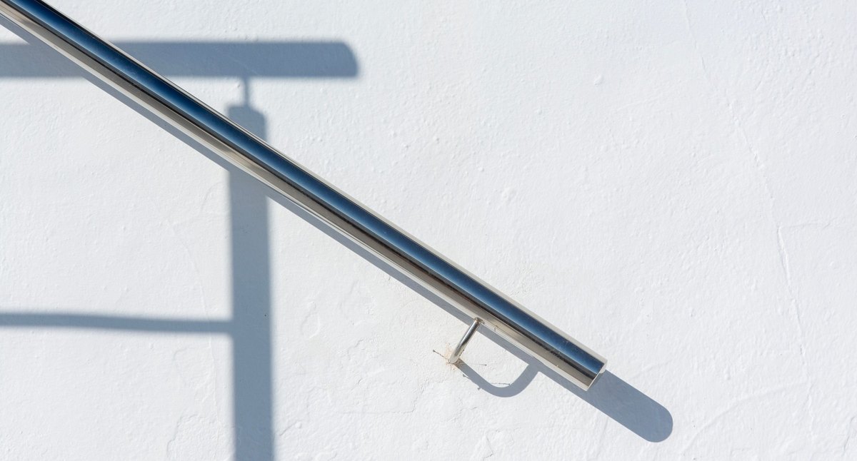 Fixation en applique d'une main courante inox sur son support : détail du point d'ancrage d'un garde-corps