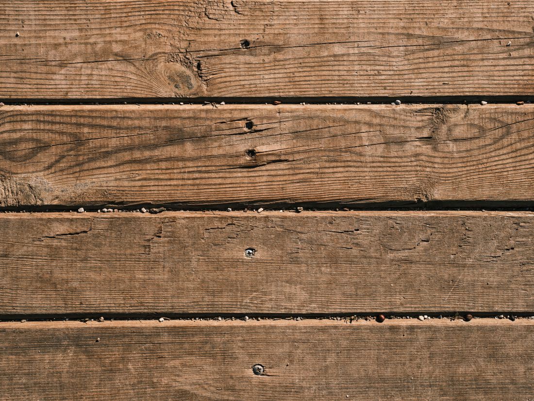 Gros plan de lames de terrasse en bois à surface brossée, jeu régulier entre lames et vis noyées