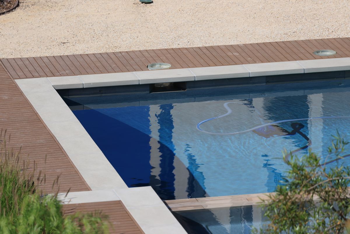Raccord d'une plage de piscine à la margelle en pierre claire, skimmer intégré et lames arrêtées à jeu constant