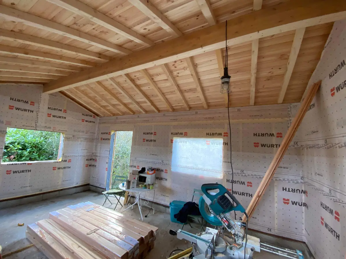 Charpente en bois apparente et parois doublées d'un pare-pluie avant la pose du bardage, construction à ossature bois de L'Esprit Bois en Gironde