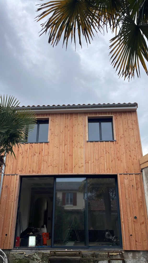 Surélévation à ossature bois : étage neuf bardé en douglas posé au-dessus du rez-de-chaussée existant, grande baie vitrée en dessous, réalisation de L'Esprit Bois en Gironde