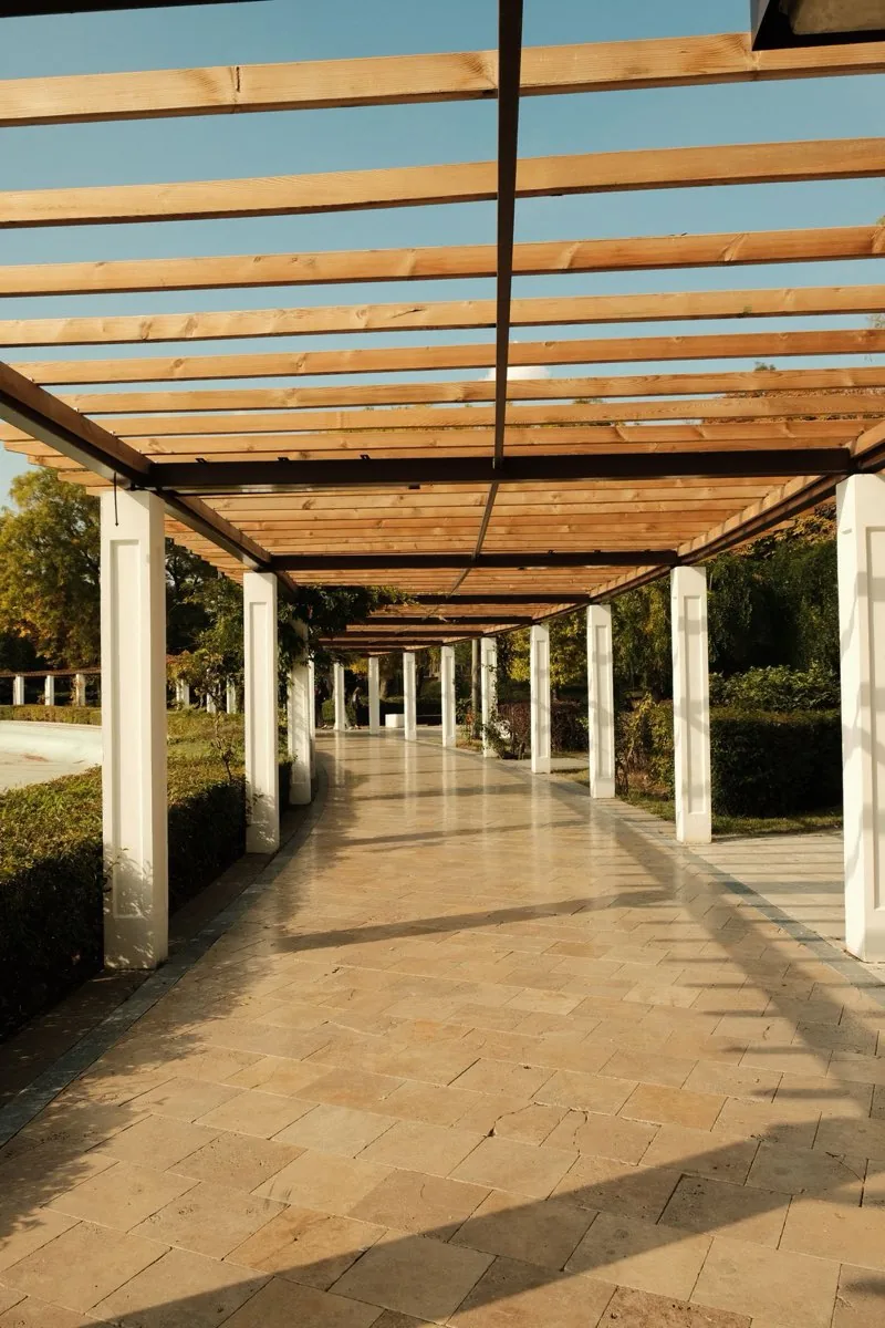 Pergola en bois massif à chevrons apparents vue en enfilade au-dessus d’une allée