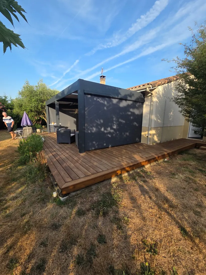 Pergola aluminium anthracite avec store screen à zip déployé sur un côté, posée sur une terrasse bois, réalisation de L'Esprit Bois à Saint-Pey-de-Castets