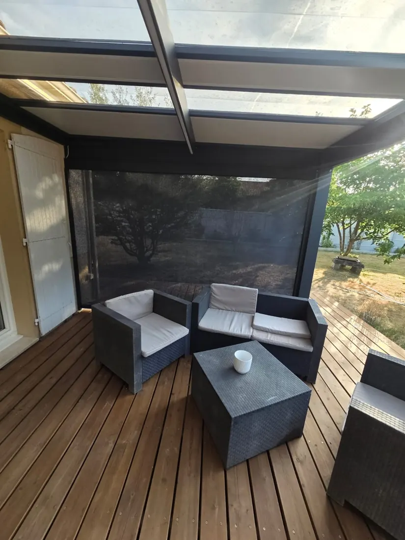 Salon de jardin abrité sous une pergola aluminium à couverture translucide, store screen descendu sur le côté, réalisation de L'Esprit Bois à Saint-Pey-de-Castets