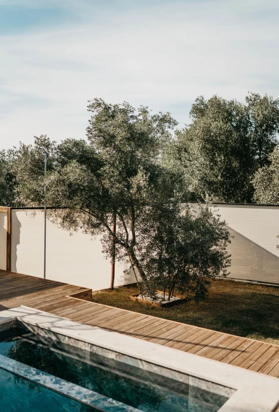 Plage de piscine en bois avec recul sur la limite séparative et écran végétal, aménagement en Gironde
